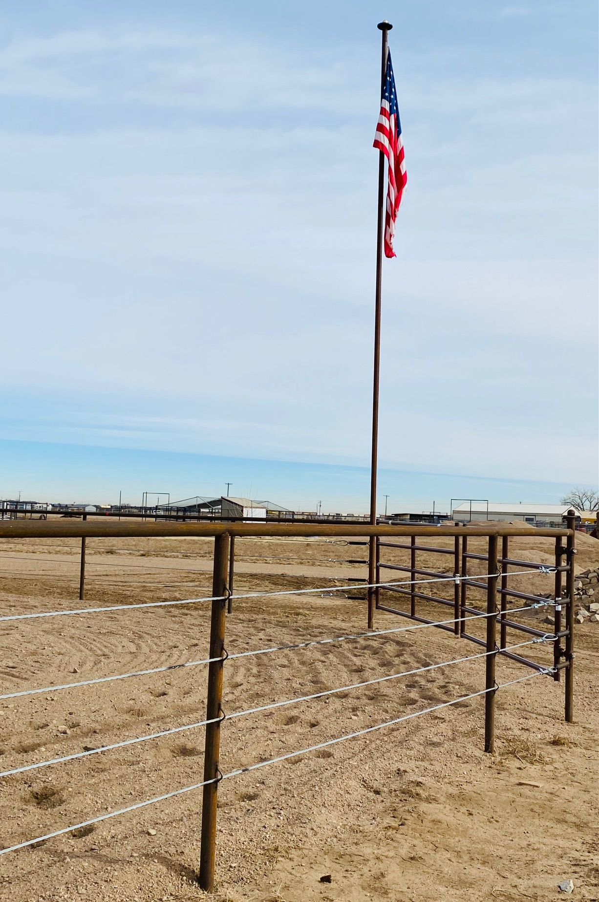 Pipe and Cable Fencing for a Riding Arena, complete with double gates and a custom flagpole. Construction by Integrity Welding Service LLC, servicing the Front Range of Colorado.